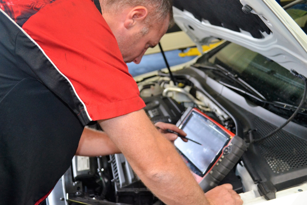 Mechanic leaning over engine bay and inspecting vehicle at Autotech Bunbury